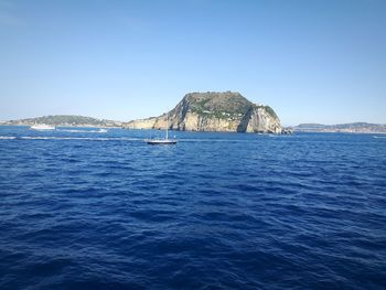 Sailboat sailing in sea against clear blue sky