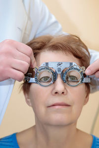 A male optometrist checks the eyesight of an adult woman with a trial frame