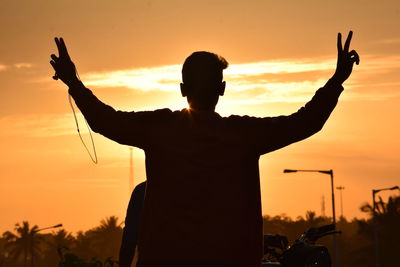 Silhouette man standing against orange sky