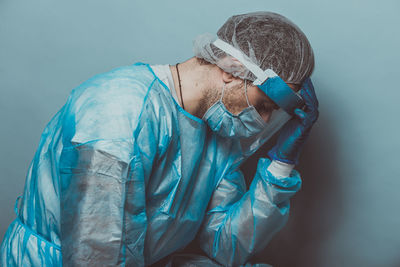 Side view of a man against blue wall