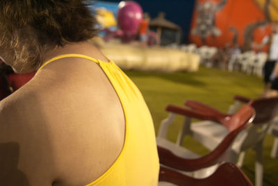 Midsection of woman in yellow top sitting outdoors at night