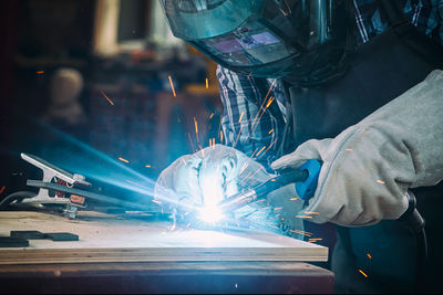 Strong man welder in work clothes hard working and welds with a welding machine metal 