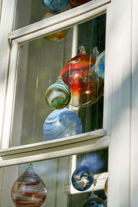 Low angle view of light bulbs hanging from glass window