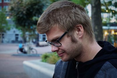 Side view of young man wearing eyeglasses looking down in park