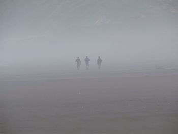 Friends walking on field during foggy weather