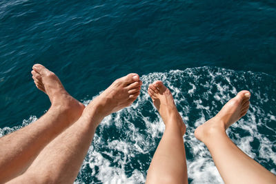 Low section of couple sitting against sea