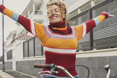 Portrait of smiling young woman standing against building