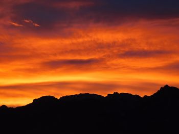 Scenic view of silhouette mountains against orange sky