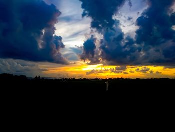 Silhouette landscape against dramatic sky during sunset