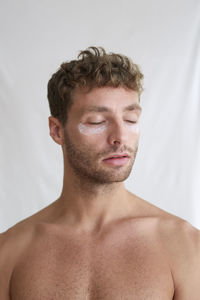 Close-up portrait of shirtless man against white background
