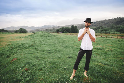 Bearded young man wearing hat standing on field