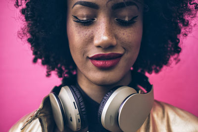 Close-up of young woman with frizzy hair against pink background