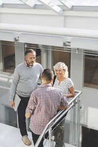 Businesspeople discussing by railing in office