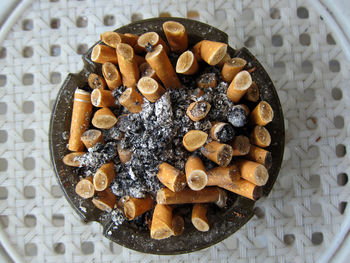 Directly above view of cigarette butts in ashtray on wicker table