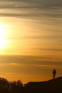 Silhouette of man standing on mountain at sunset