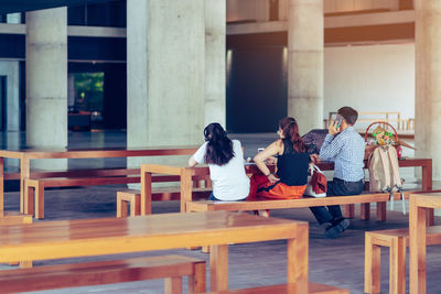Rear view of people sitting on table