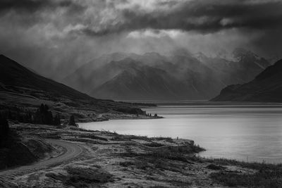 Scenic view of river and mountains against cloudy sky