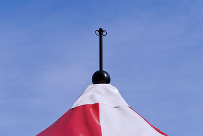 Low angle view of cross on pole against clear blue sky