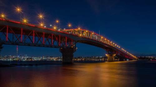 Illuminated bridge over river at night