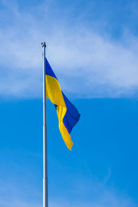 Low angle view of flag against blue sky