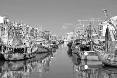 Boats moored at harbor against sky