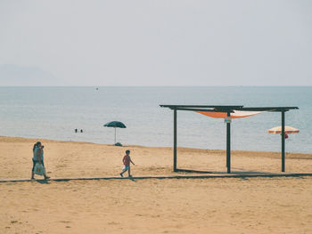 People on beach against clear sky