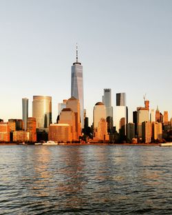 Sea by buildings in city against clear sky