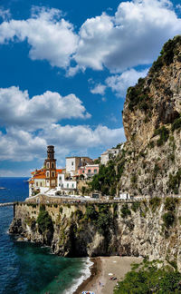 Buildings by sea against sky