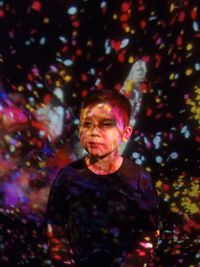 Portrait of man standing against illuminated wall