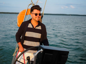 Handsome person steering wheel sailing yacht or sailboat on a summer vacations 