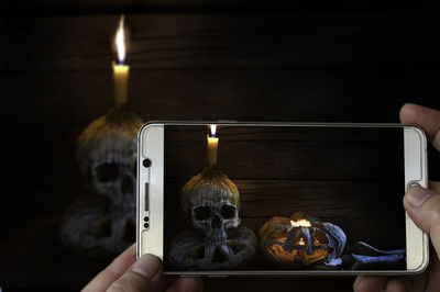 Cropped hands of person photographing spooky halloween decorations with mobile phone