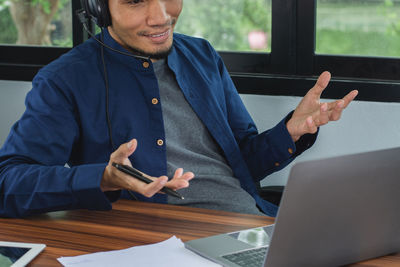 Midsection of man using mobile phone while sitting on table