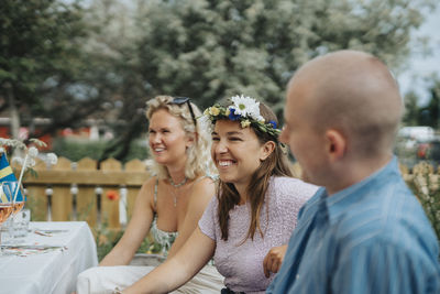 Smiling young woman wearing tiara while enjoying with friends during dinner party at cafe