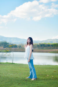 Rear view of woman standing on field against sky