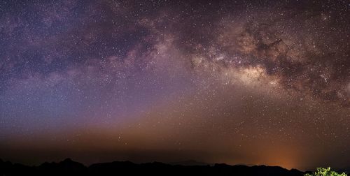 Silhouette landscape against star field at night