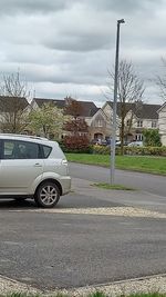 Car on street by buildings against sky