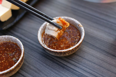 High angle view of food in chopsticks over bowl on table