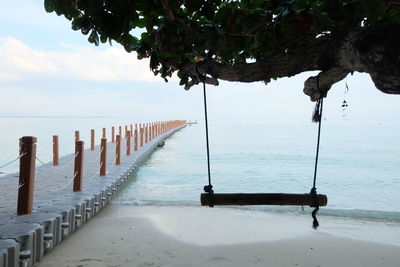 Wooden posts on beach against sky