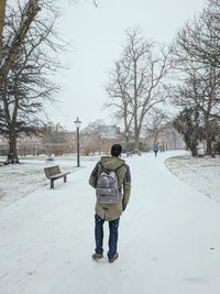 Rear view of man walking on snow covered field