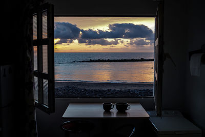 View of sea seen through window during sunset