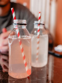 Two bottles of lemonade with red straws on the wooden table 