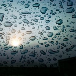 Low angle view of raindrops on glass window