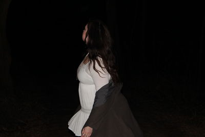 Rear view of woman standing against black background