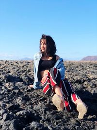 Woman on rocks against clear sky