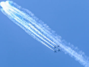 Low angle view of airplanes against blue sky