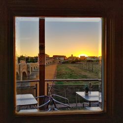 Buildings seen through glass window against sky during sunset