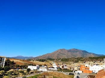 Town by mountains against clear blue sky