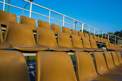 Low angle view of empty bleachers at stadium against clear blue sky