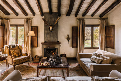 Spacious living room with couch and soft cushions near table and fireplace in hunting house