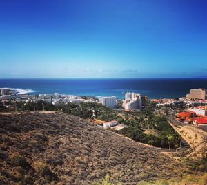 High angle view of buildings and sea against clear blue sky